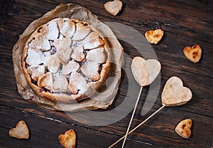 Idea for the celebration of Valentine`s Day: cherry pie with the decor the dough in the shape heart on wooden table.