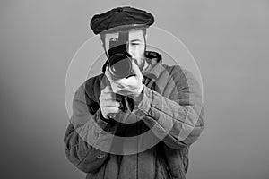 Idea- cinema industry. Cameraman with retro camera in his hands, studio shot, monochrome effect. Bearded man in old-fashioned