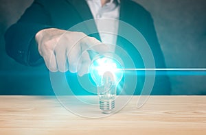 Idea concept. businessman holds a glowing light bulb in his hand on blue background. banner. Successful business idea and creative