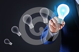 Idea concept. Businessman touching glowing light bulb on virtual screen