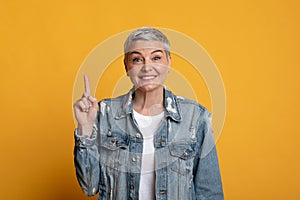 Idea Concept. Inspired mature woman pointing finger upwards