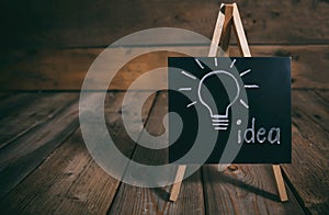 Idea concept. Light bulb drawn on a chalkboard, dark wooden background