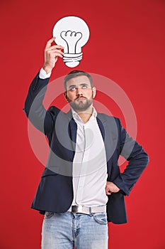 Idea concept. Man in a jacket holding idea bulb under his head