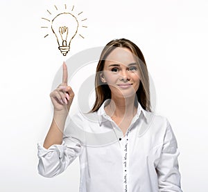 Idea concept. Smiling young woman pointing a finger at idea light bulb. Isolated on white
