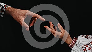 Idea of earth creation. Ukrainian hands reaching out, pointing finger together on black background. Man and woman in