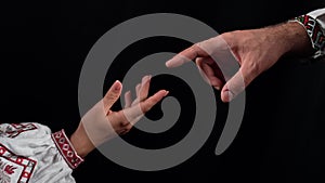 Idea of earth creation. Ukrainian hands reaching out, pointing finger together on black background. Man and woman in