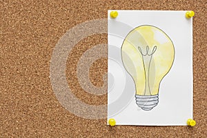 Idea, invention concept. Light bulb hand drawn on paper pinned to cork board with copy space