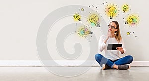 Idea light bulbs with woman using a tablet