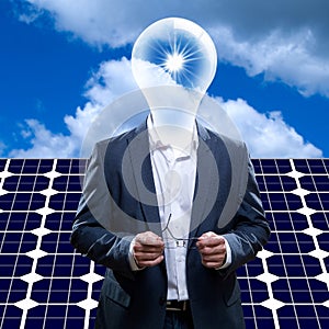Idea man with light bulb head standing in front of a solar panel and blue sky and sun