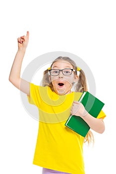 Idea. Points a finger up. Cheerful young child girl with glasses holding a book to study isolated on a white background.