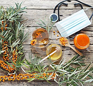 The idea of protecting and treating influenza with folk remedies using the healthy sea buckthorn berry.Medical mask with a