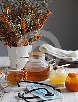 The idea of protecting and treating influenza with folk remedies using the healthy sea buckthorn berry.Medical mask with a