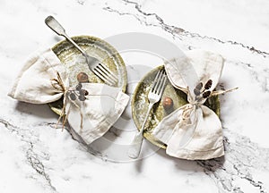 Idea of serving is vintage ceramic plates and linen napkins decorated with cones and nuts on a light marble background, top view