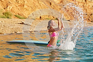 Idea of summer time, surf sport, desire of adventure, copy space. Beautiful girl in sea water in swimsuit and surfboard