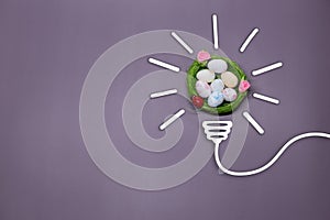 Idea symbol in the form of a painted light bulb with decorative Easter basket with eggs inside on a purple background