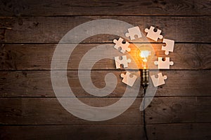 Idea and teamwork business concept, vintage incandescent light bulb and jigsaw on the wooden background