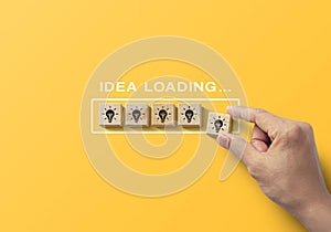 Idea uploading, reboot idea, refresh or creative mindset concept. Hand putting wooden blocks in progress bar on yellow background