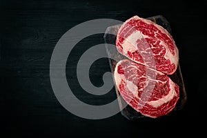 Ideal raw rib eye beef steak on black wooden background