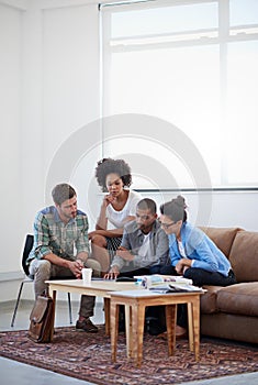 The ideas are coming now. a group of designers having a meeting around a coffee table.