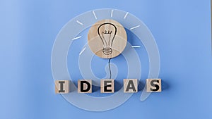 Ideas concept with light bulb and wooden cubes on blue background. Creative thinking ideas and innovation concept
