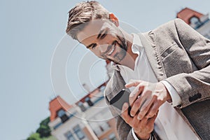 Ideas are easy. Implementation is hard. Serious brown-haired man is looking in his phone while standing in the park. He