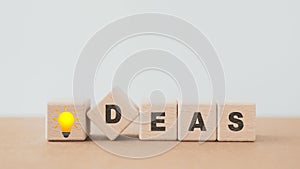 Ideas text with brilliant lightbulb instead of I, on wooden cube blocks including copy space. For Positive thinking, motivation