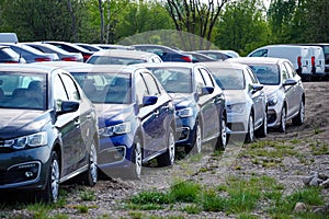 Identical blue cars stand in a row in a Parking lot or market for sale. View of the side mirrors, the Dealership. New car sales.