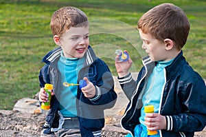 Identical twin brothers blow soap bubbles