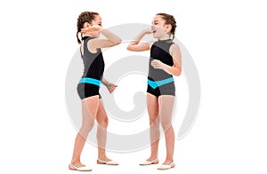 Identical twin girls practice and doing rhythmic gymnastics, white background