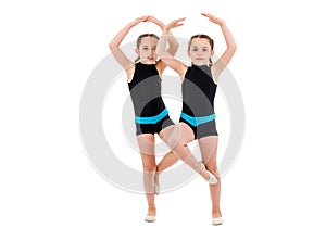 Identical twin girls practice and doing rhythmic gymnastics, white background