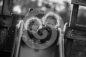 Identical twin girls on slide on playground