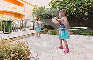 Identical twin sisters are playing on vacation with hula hoop