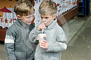 Identical twins are drinking tea in the park