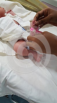 Identification tag being put on the feet of new born infant in hospital