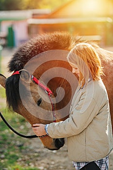 Idilic image of a ginger girl petting her horse looking with love