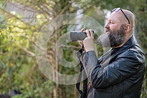Idiosyncratic crazy artist with beard, holds a digital system camera
