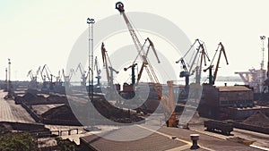 Idle sea port cranes and black piles of coal.