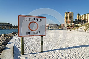 Idle Speed No Wake sign on a white sand at the beach shore near the hotels at Destin, Florida