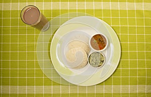 Idli with chutney Indian vegetarian foods - chocolate milk glass on a green check cloth mat