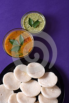 Idli with Sambar and coconut chutney on violet background, Indian Dish