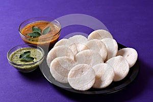 Idli with Sambar and coconut chutney on violet background, Indian Dish