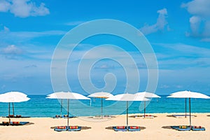 Idollic beach relaxing concept with white parasols on sand