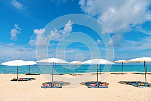 Idollic beach relaxing concept with white parasols on sand