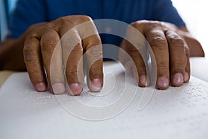 idsection of senior man reading braille book in nursing home