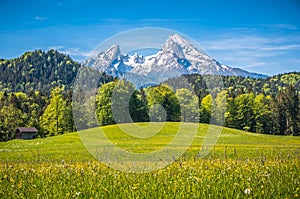 Idyllic alpine landscape with green meadows, farmhouses and snowcapped mountain tops photo