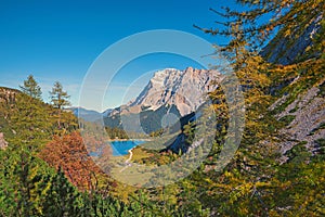 Idyllic alpine landscape with lake view Seebensee, larch trees and forest in autumn