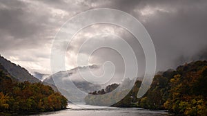 Idyllic autumn landscape with a lake covered in dark clouds and mist