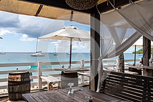 Idyllic beach restaurant with wooden tables and benches and white umbrellas