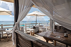 Idyllic beach restaurant with wooden tables and benches and white umbrellas