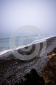 Idyllic beach scene with tranquil ocean fog rolling in and wispy clouds above